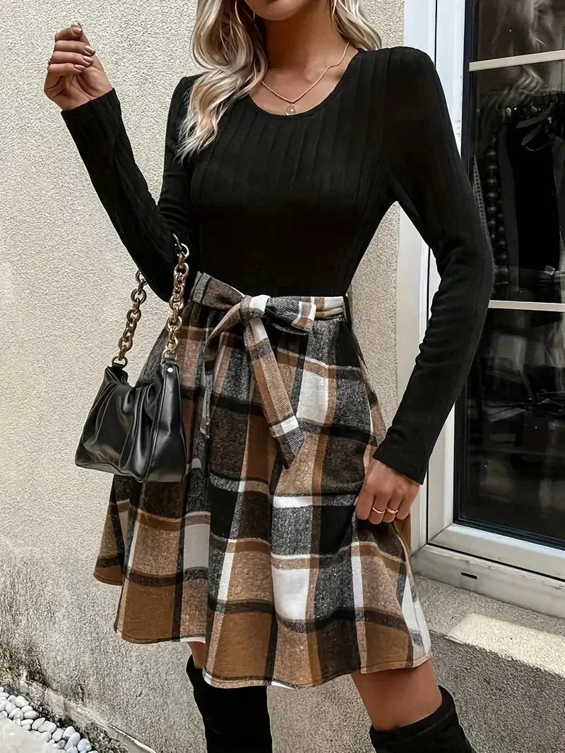 Haut ajusté noir à manches longues, jupe évasée à carreaux, tissu doux et imprimé classique pour un look moderne.