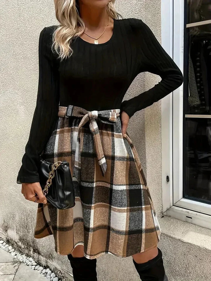 Haut ajusté noir en coton avec manches longues, associé à une jupe évasée à carreaux en tissu léger.
