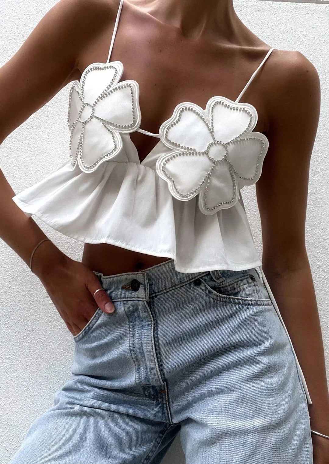 Haut court en coton avec appliques florales, conçu avec de fines bretelles pour un look léger et féminin.