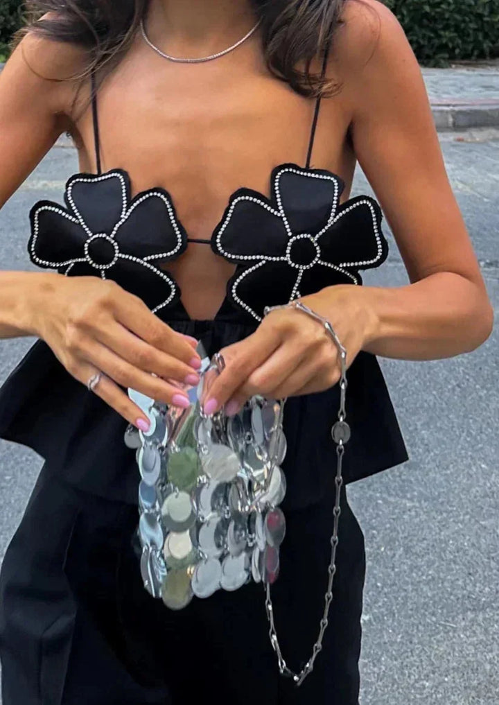 Haut court noir femme en tissu léger, avec appliques florales délicates et fines bretelles ajustables pour un style élégant.