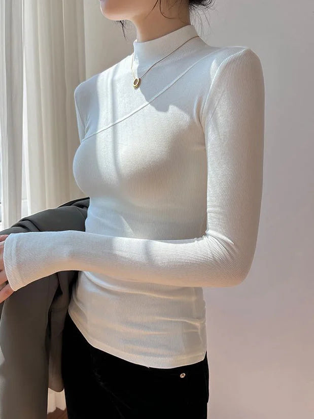 Haut femme blanc, col montant, manches longues, en tissu extensible pour un ajustement confortable.