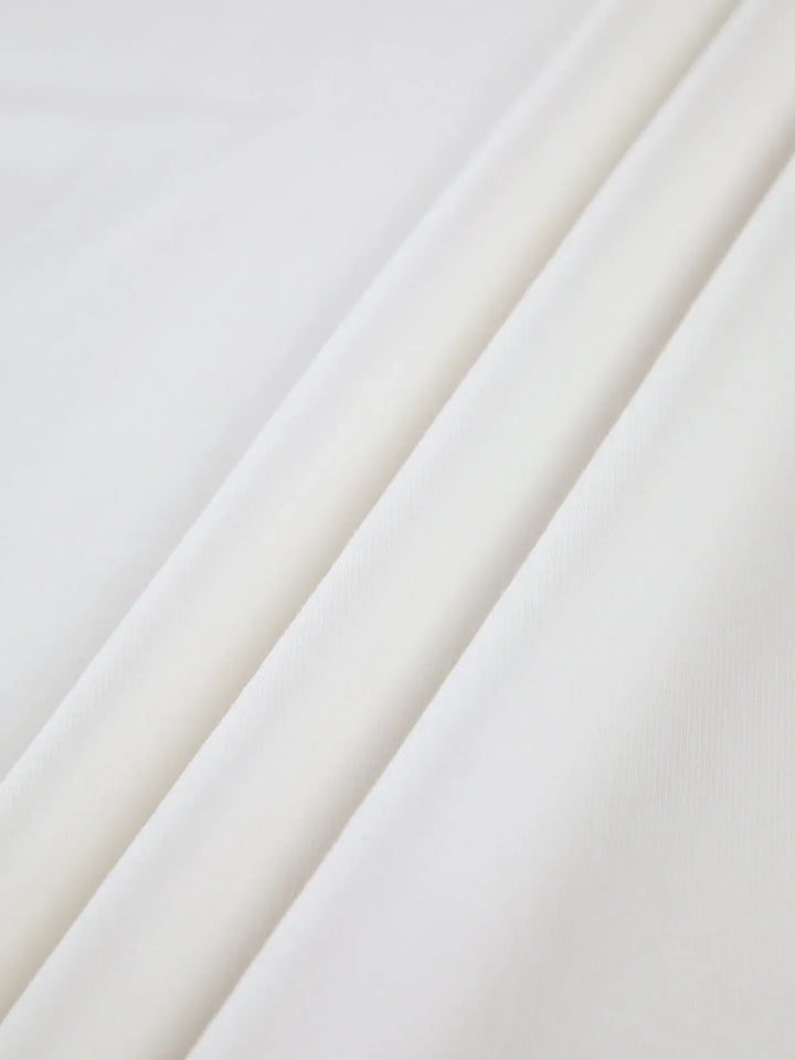 Haut femme blanc col montant, manches longues, en tissu extensible, idéal pour des tenues variées.