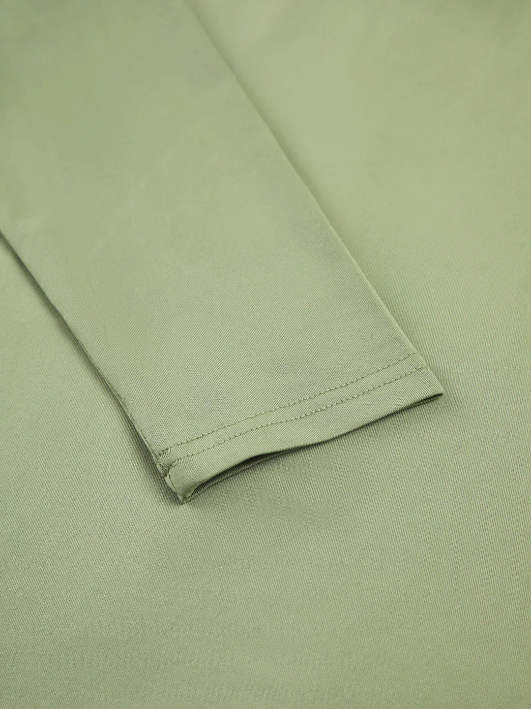 Haut femme verte clair à manches longues, en tissu extensible, coupe ajustée pour un bon confort.