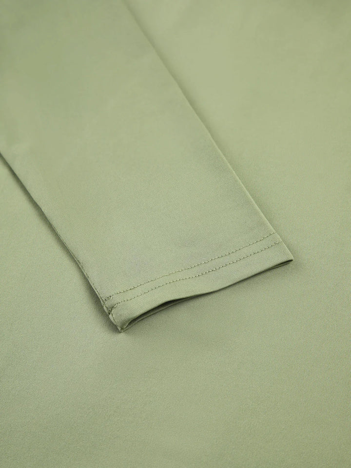Haut femme verte clair à manches longues, en tissu extensible, coupe ajustée pour un bon confort.