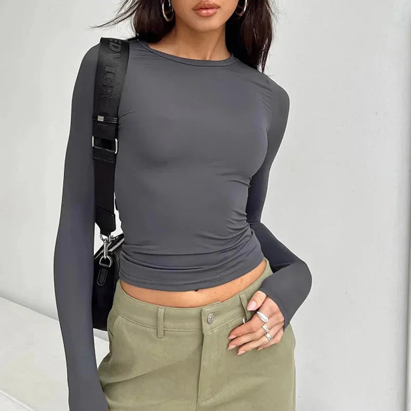 Haut slim femme blanche à manches longues, en tissu extensible, coupe ajustée pour un usage quotidien.