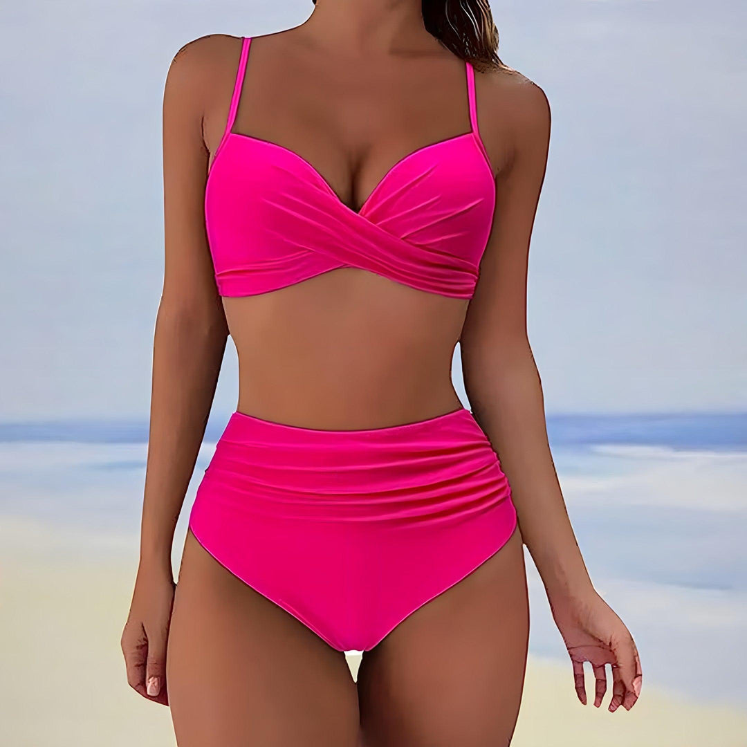 Donna in bikini rosa acceso, design a vita alta, sfondo spiaggia. Costume da bagno estivo, moda mare, abbigliamento donna.