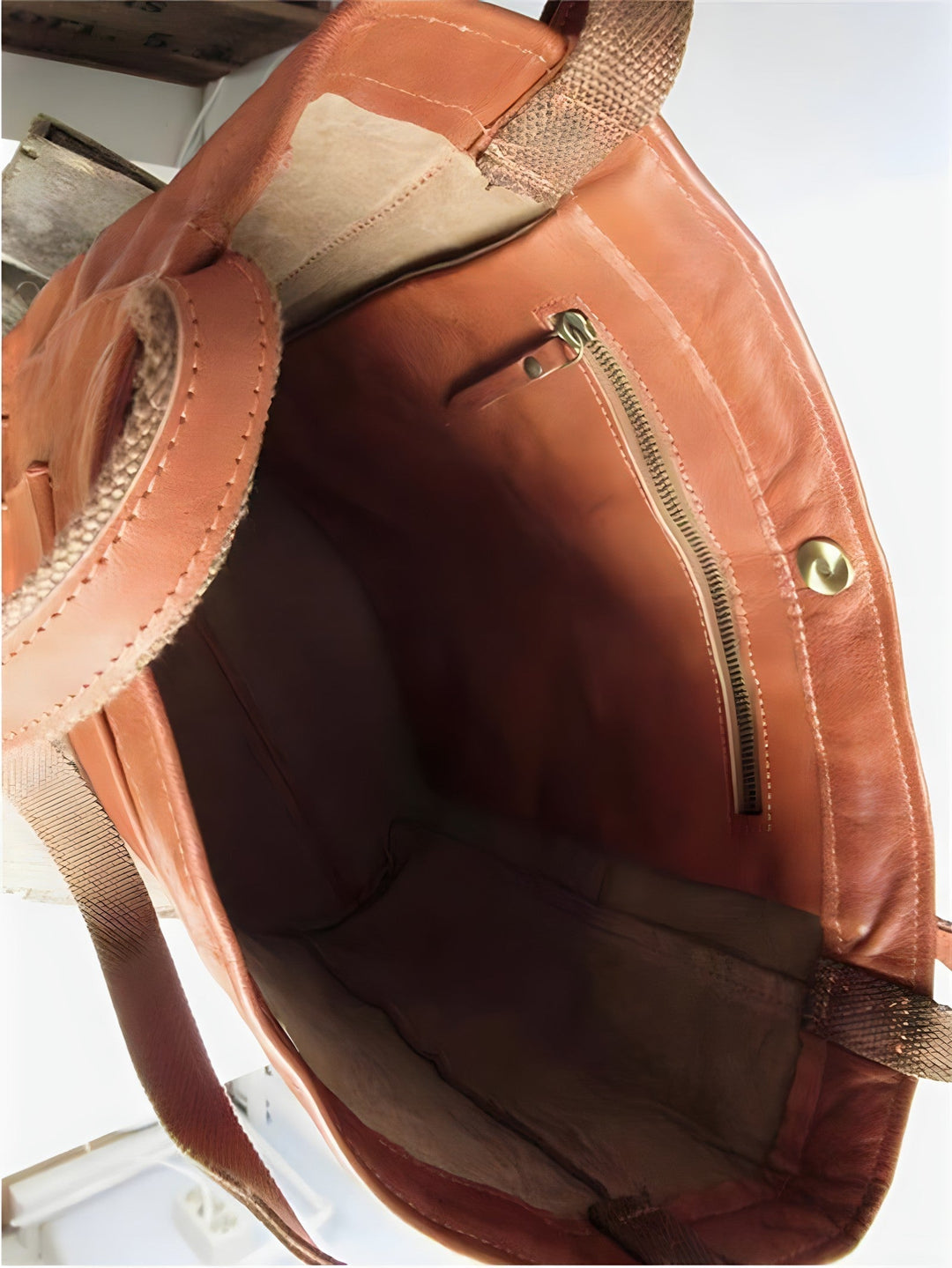 Interno di una borsa in pelle marrone con tasca interna con cerniera e chiusura a bottone. Design elegante e spazioso. Accessorio moda donna.