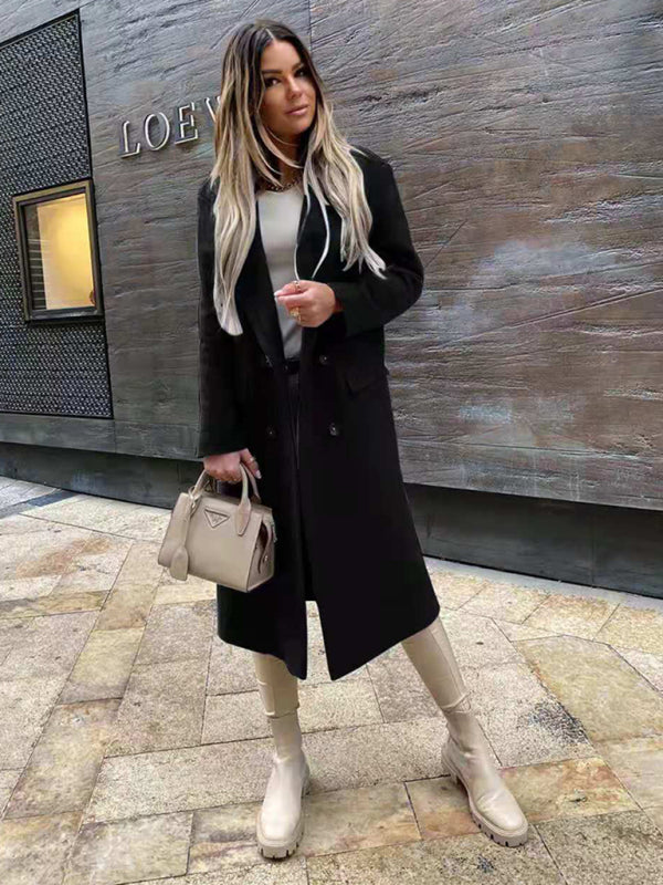 Donna con cappotto nero e stivali beige, borsa Prada, posa su marciapiede urbano. Moda autunnale, stile elegante, capelli lunghi biondi.