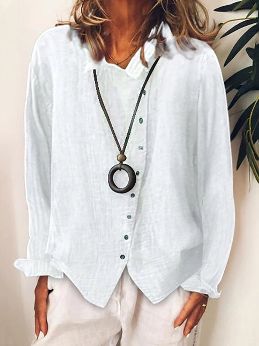 Camicia bianca in lino da donna con bottoni verdi, abbinata a collana con ciondolo circolare. Moda casual elegante, abbigliamento estivo.