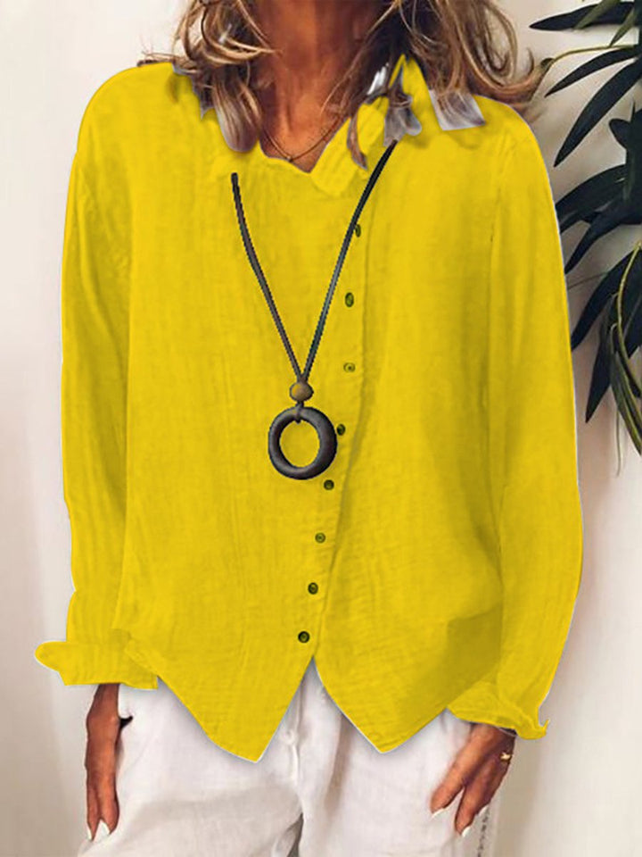 Camicia donna gialla in lino, maniche lunghe, abbinata a collana nera con ciondolo rotondo. Moda casual estiva, stile elegante e leggero.