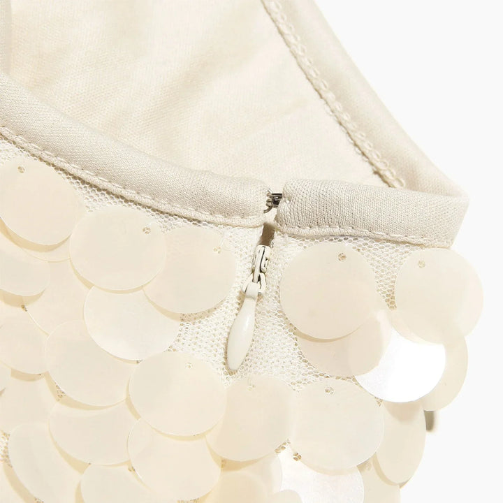 Jupe courte en sequins ivoire avec une finition scintillante, parfaite pour une soirée festive. Tissu léger et ajusté.