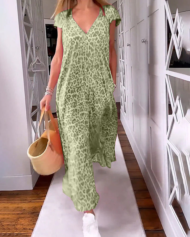 Donna con abito lungo leopardato verde, borsa di paglia e scarpe bianche, cammina in corridoio moderno. Moda estiva, abbigliamento casual chic.