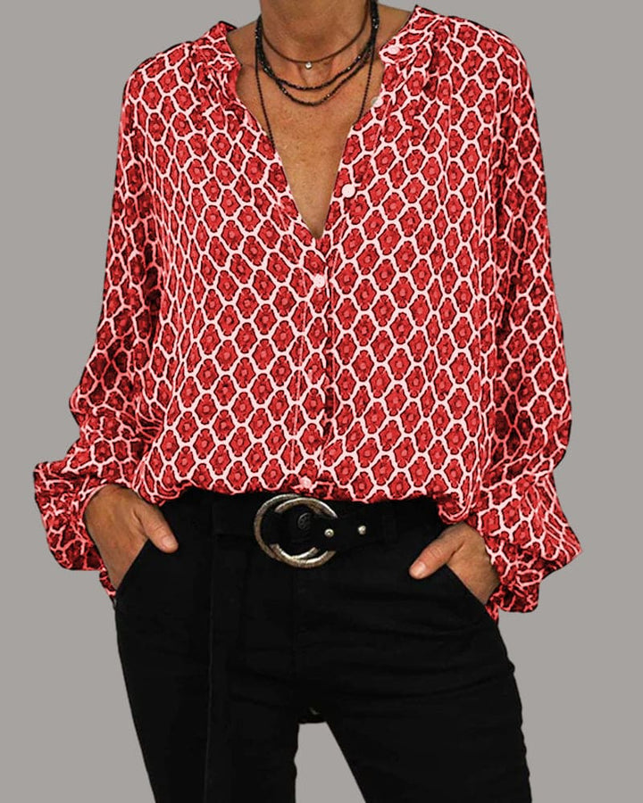 Camicia donna rossa a fantasia geometrica, maniche lunghe, scollo a V, abbinata a pantaloni neri e cintura con fibbia. Moda casual elegante.