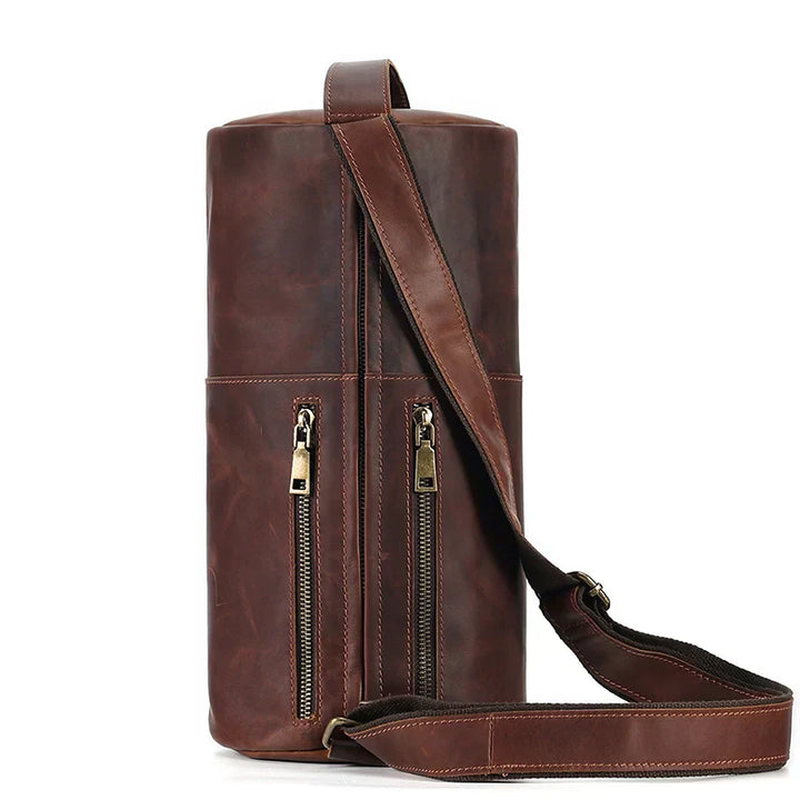Borsa a tracolla cilindrica in pelle marrone con doppia cerniera e tracolla regolabile. Design elegante e pratico per uomo e donna.