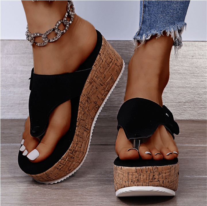 Sandali donna con zeppa in sughero, cinturino nero, indossati con jeans strappati e cavigliera a catena. Scarpe estive eleganti e comode.