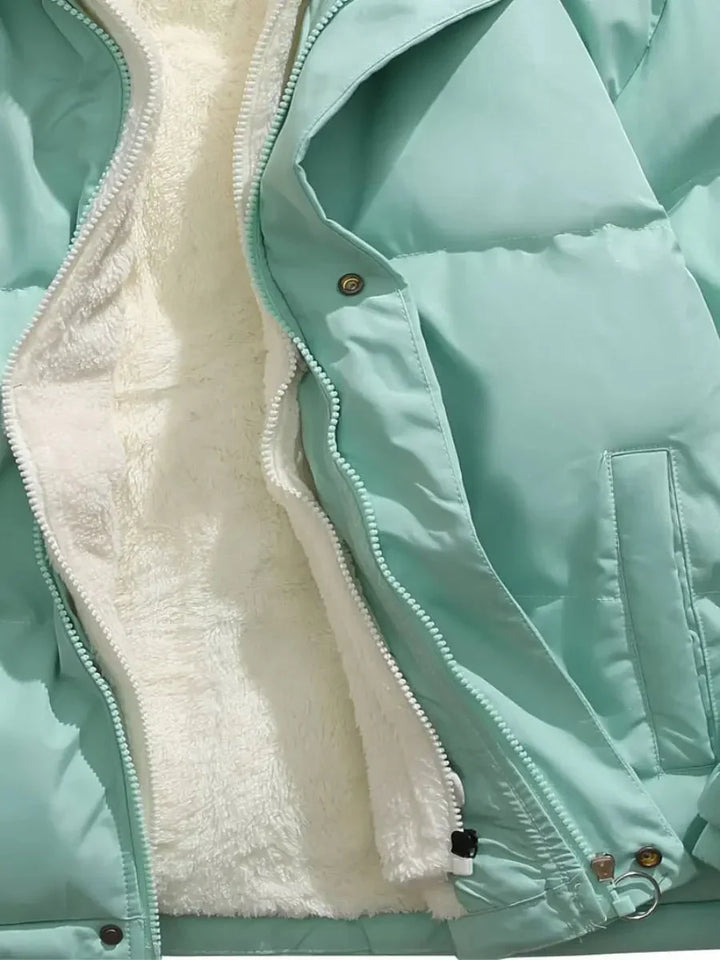 Doudoune d'hiver femme bleue avec capuche, doublure en polaire et extérieur résistant au vent.