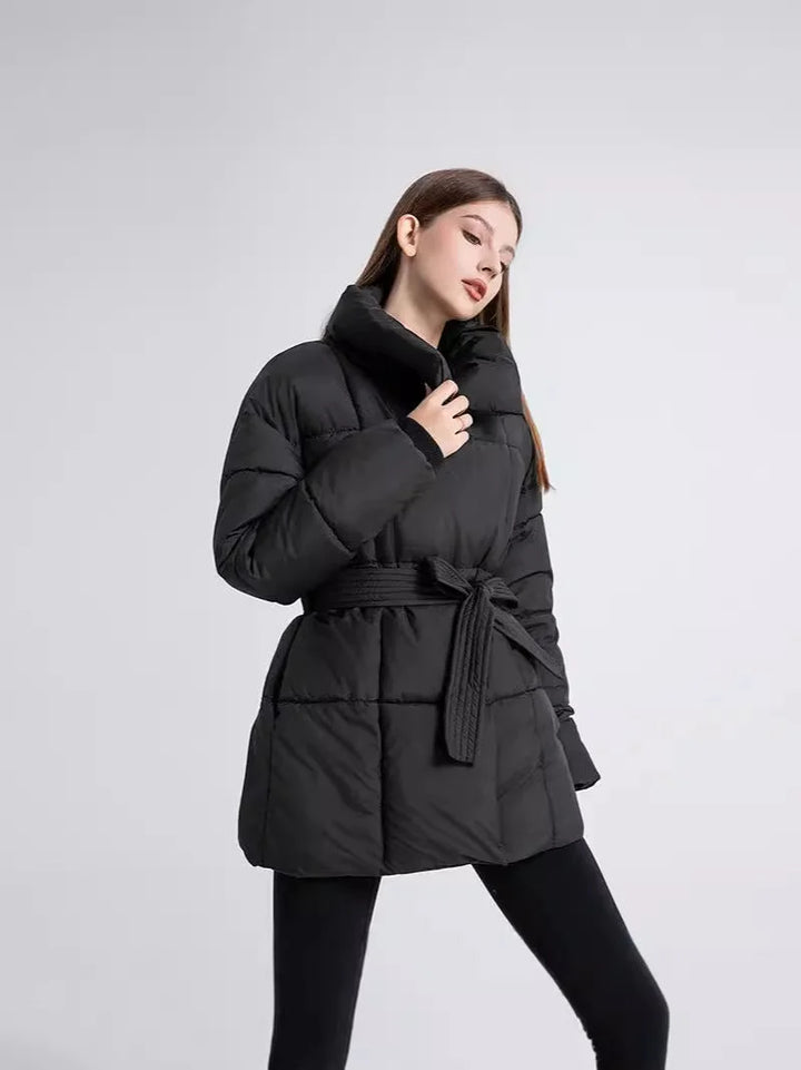 Manteau d'hiver femme noir avec ceinture et col élégant, en matériau chaud, adapté pour les jours froids.