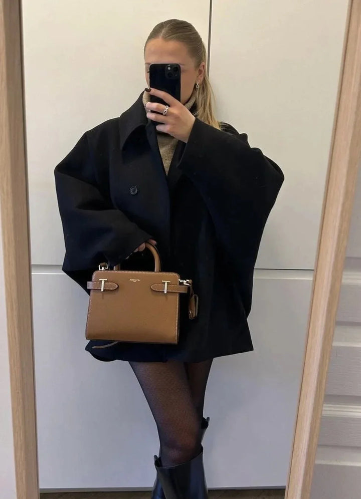 Manteau ample noir pour femme avec grands revers et boutons, adapté pour les journées fraîches et les tenues décontractées.