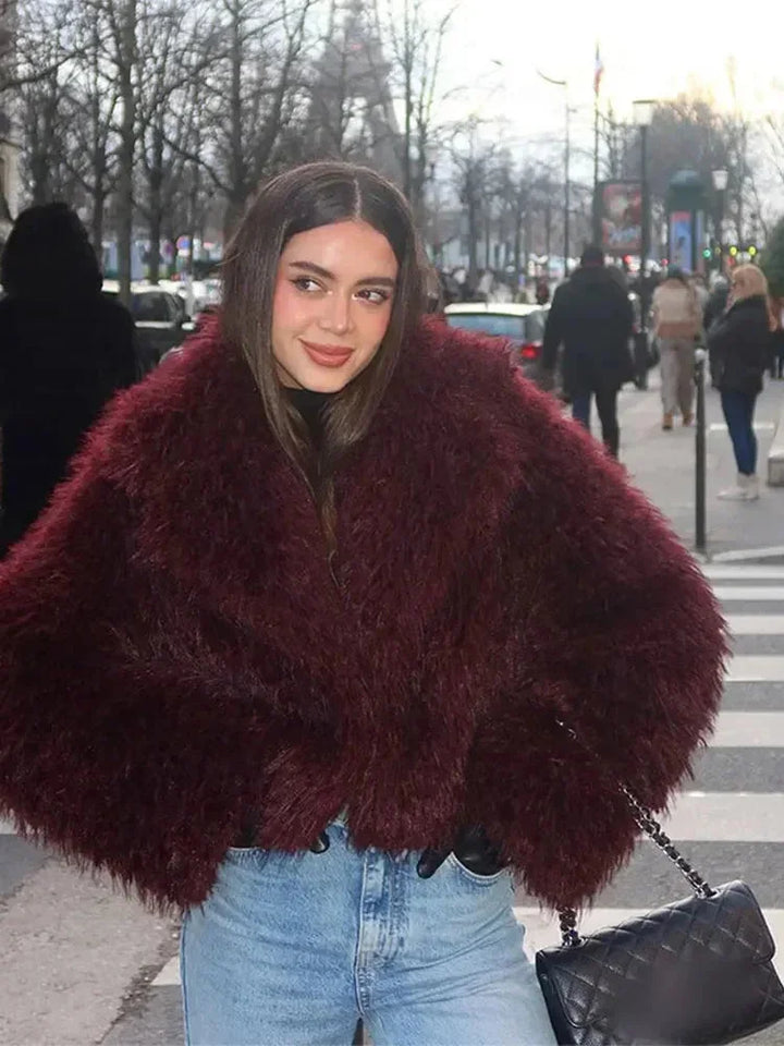 Manteau bordeaux en fausse fourrure avec grand col, adapté pour les journées fraîches.