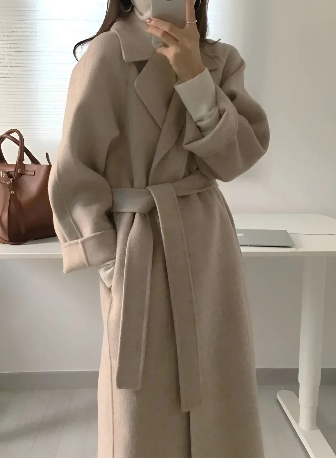 Manteau long marron pour femme avec ceinture et col chic, en tissu doux et résistant, au design classique.