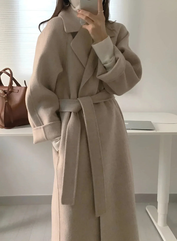 Manteau long marron pour femme avec ceinture et col chic, en tissu doux et résistant, au design classique.