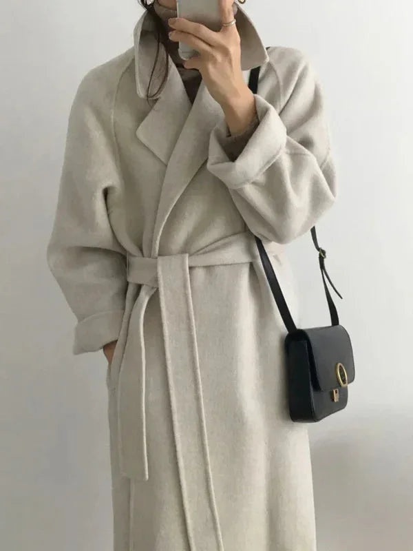 Manteau long marron pour femme, ceinture à la taille et col chic, adapté pour les journées fraîches.
