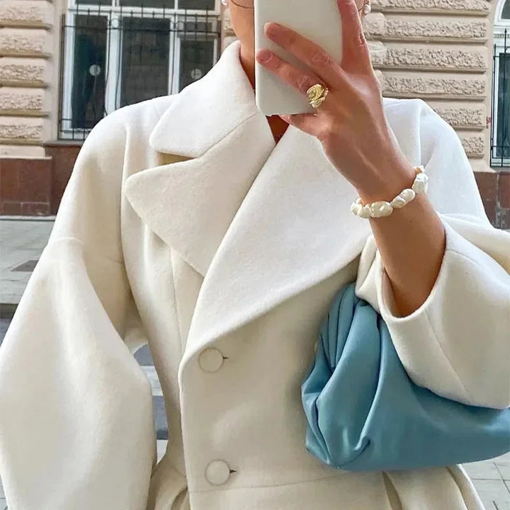 Manteau long blanc pour femme avec col large et coupe élégante et simple.
