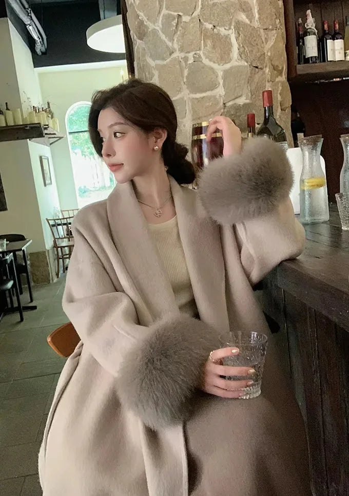 Manteau long noir pour femme, ceinturé, avec manches en fausse fourrure.