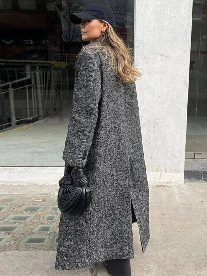 Manteau long gris pour femme, manches longues, en tissu fluide avec un design moderne.