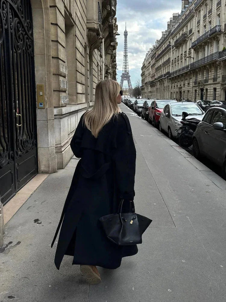 Manteau long noir femme avec ceinture, larges revers et tissu chaud, adapté pour les journées fraîches.