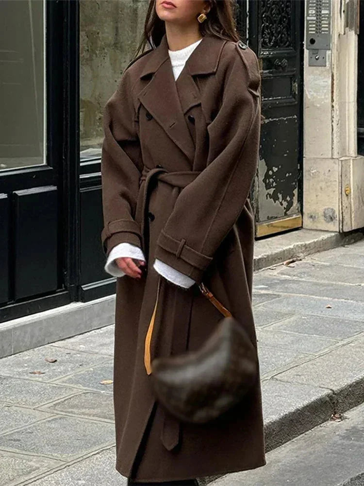 Manteau mi-long noir femme avec ceinture large, boutons décoratifs et coupe cintrée.