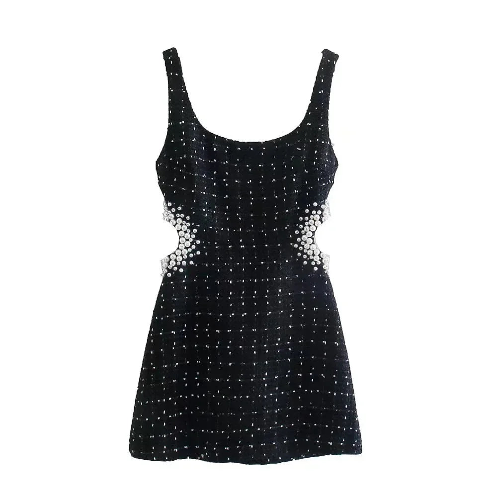 Mini robe noire en tissu léger, ornée de perles, avec découpes élégantes et manches épaules nues pour un look sophistiqué.