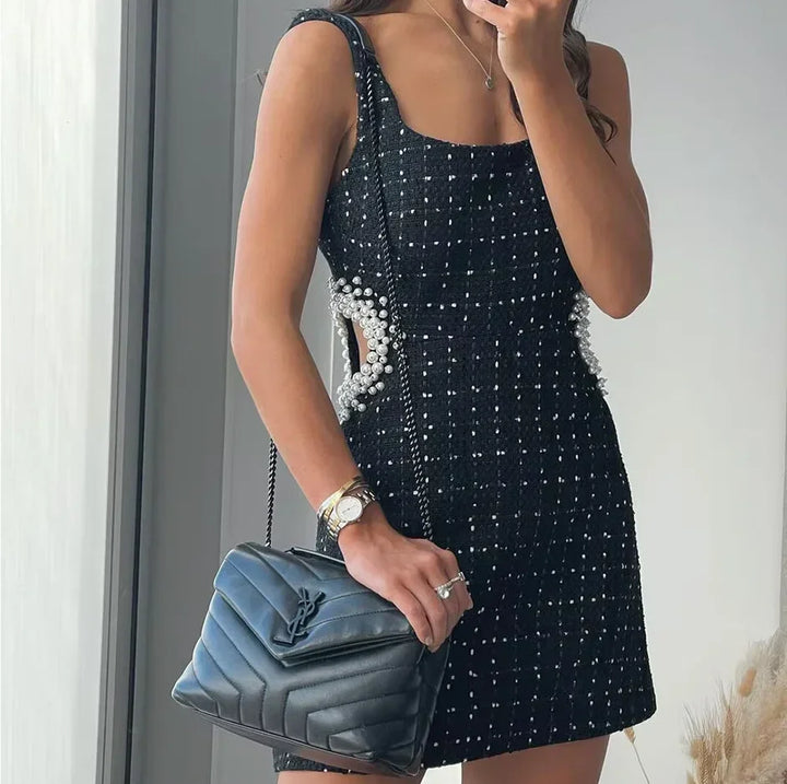 Mini robe noire en tissu léger, perlée, avec découpes et manches épaules nues, parfaite pour les soirées et événements.