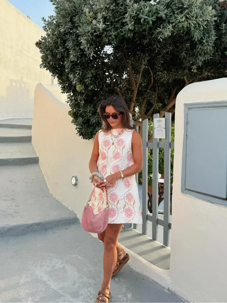 Mini robe sans manches en tissu léger, ornée de fleurs roses, idéale pour les journées d'été. Design frais et fluide.