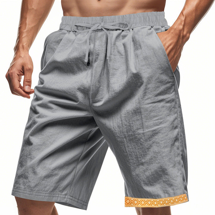 Pantaloncini sportivi grigi da uomo con tasche, elastico in vita e bordo decorativo arancione. Ideali per fitness e attività all&