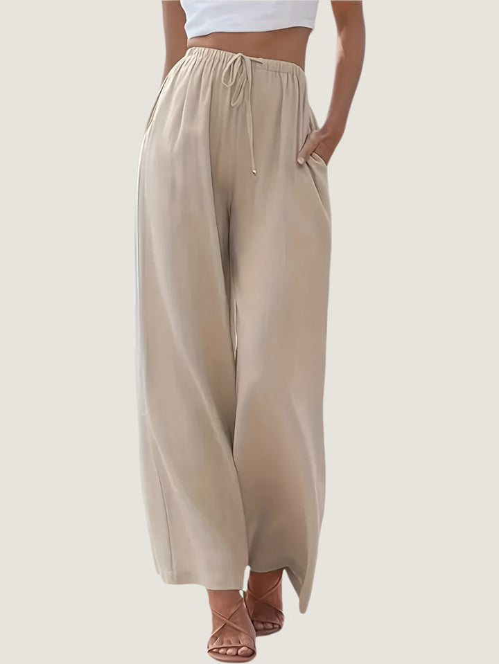 Pantaloni palazzo beige da donna, vita alta con coulisse, tessuto leggero, tasche laterali, abbinati a top bianco. Eleganti e comodi per l&