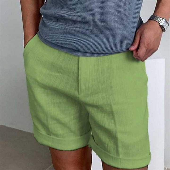 Uomo con pantaloncini verdi casual, maglietta grigia, orologio al polso. Moda estiva maschile, abbigliamento leggero e confortevole.