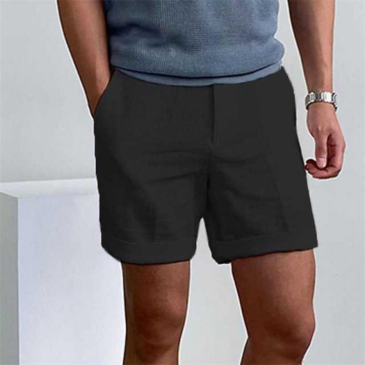 Uomo con pantaloncini neri casual, maglietta grigia, orologio al polso. Moda estiva maschile, abbigliamento comodo, stile urbano.