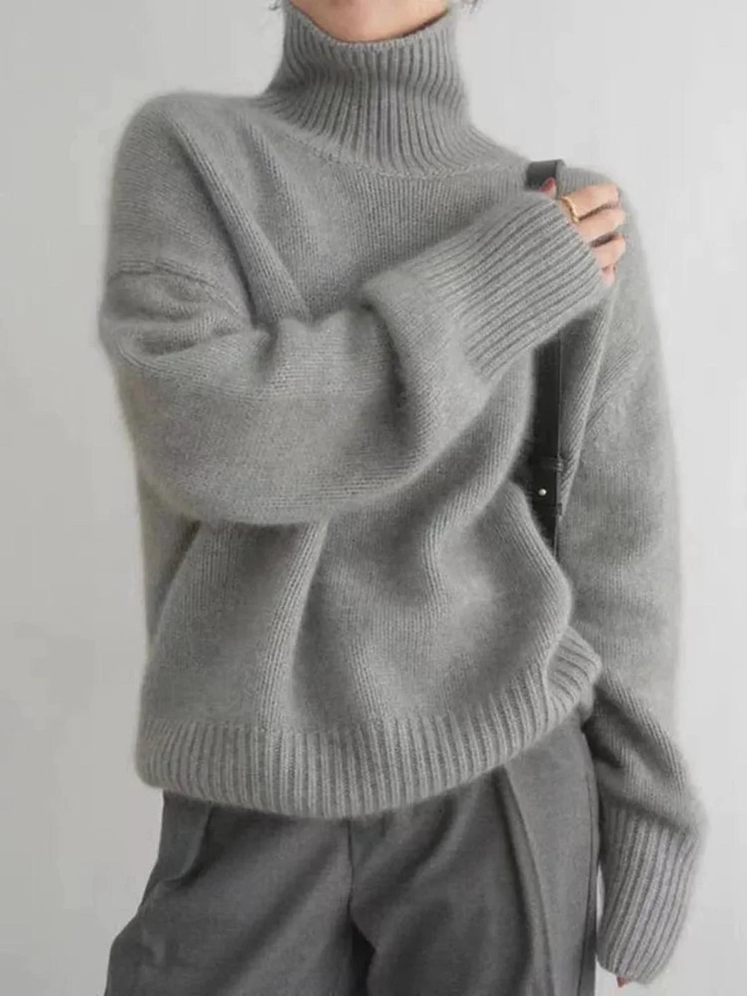 Pull beige à col roulé, en maille côtelée, offrant une coupe confortable et des possibilités de styles variés.