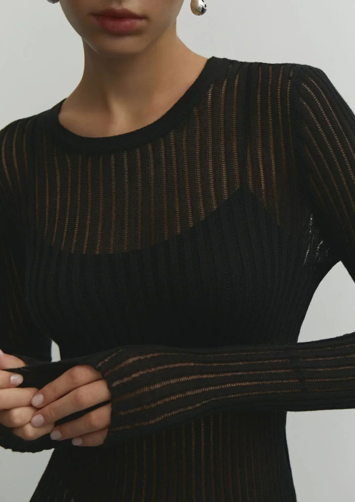 Pull femme noir en maille côtelée, style décontracté avec des emmanchures longues et des motifs ajourés.