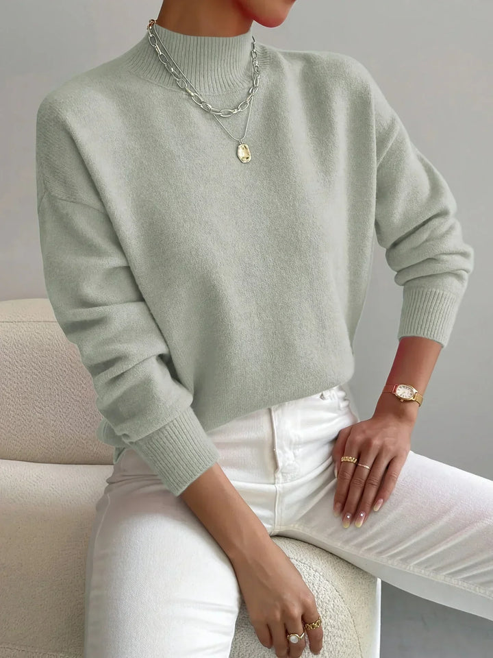 Pull féminin rose clair à col montant, en tissu extensible, avec manches longues pour un ajustement confortable.