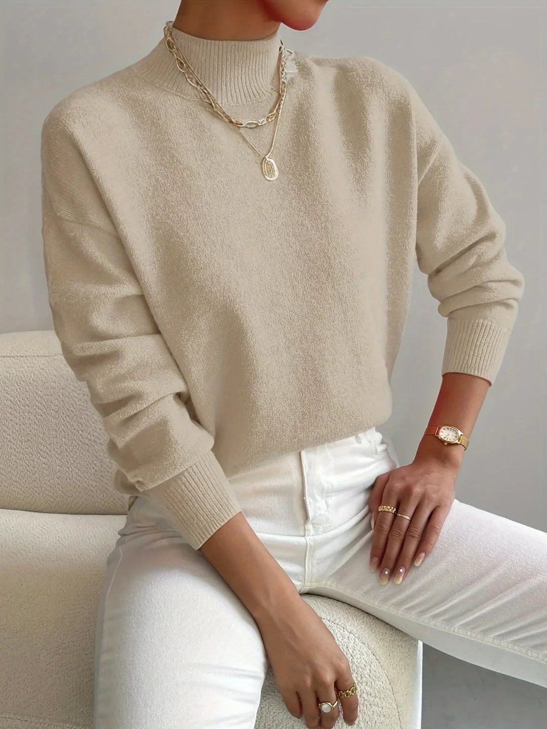Pull blanc féminin à col montant, en tissu extensible, manches longues et coupe simple.