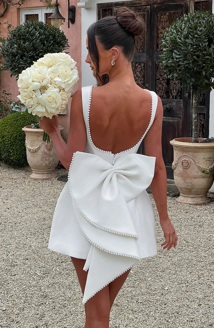 Robe courte femme en tissu léger, avec nœud décoratif au dos et coupe élégante, parfaite pour les occasions décontractées.