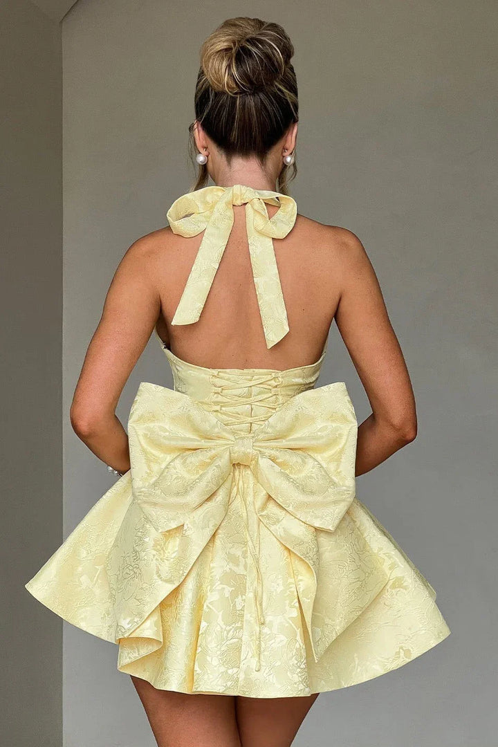 Robe courte femme en tissu léger, dos nu, avec un design plissé et des bretelles fines pour un look élégant.