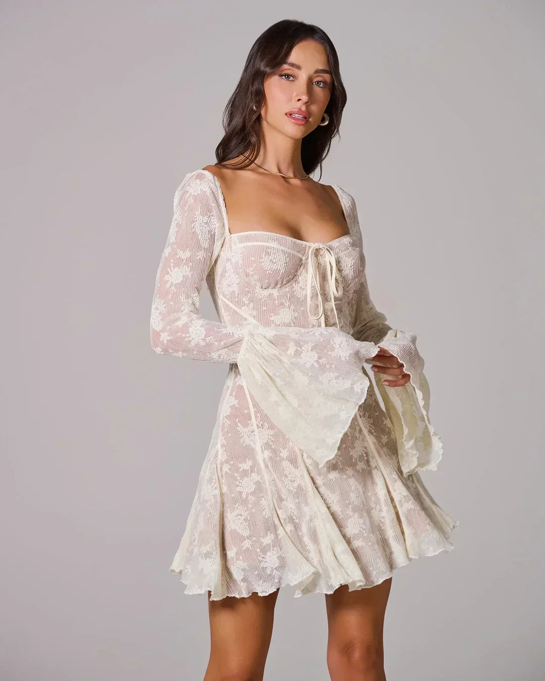 Robe courte femme en dentelle blanche, légère, avec des manches courtes et un détail de broderie florale délicate.