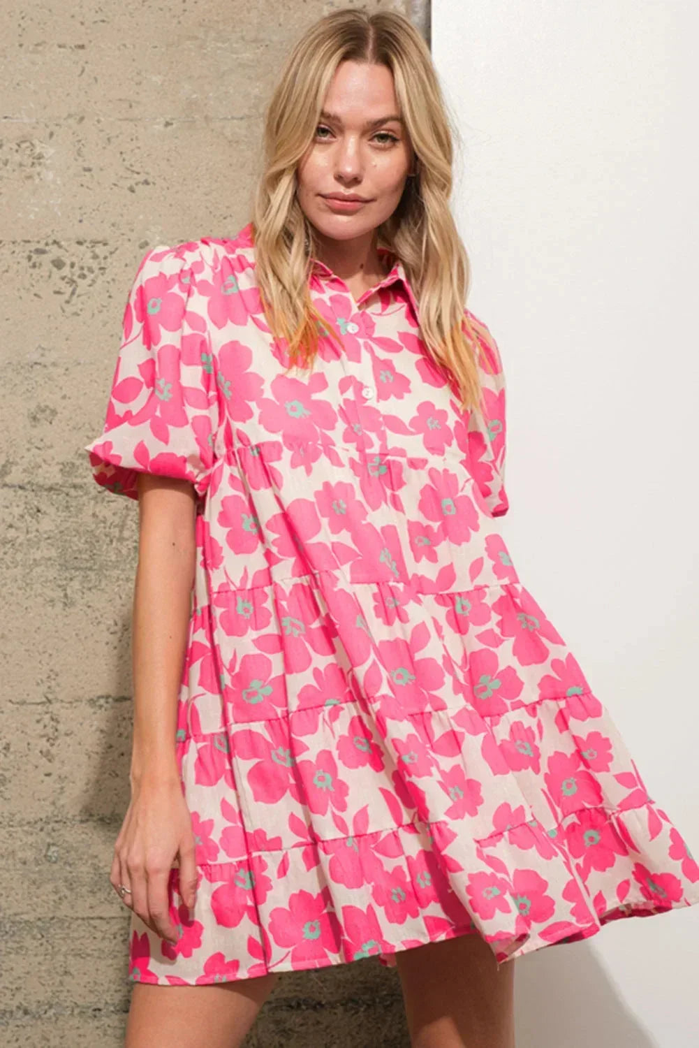 Robe courte en coton rose, motifs fleuris, volants sur le bas, manches bouffantes pour un look estival décontracté.