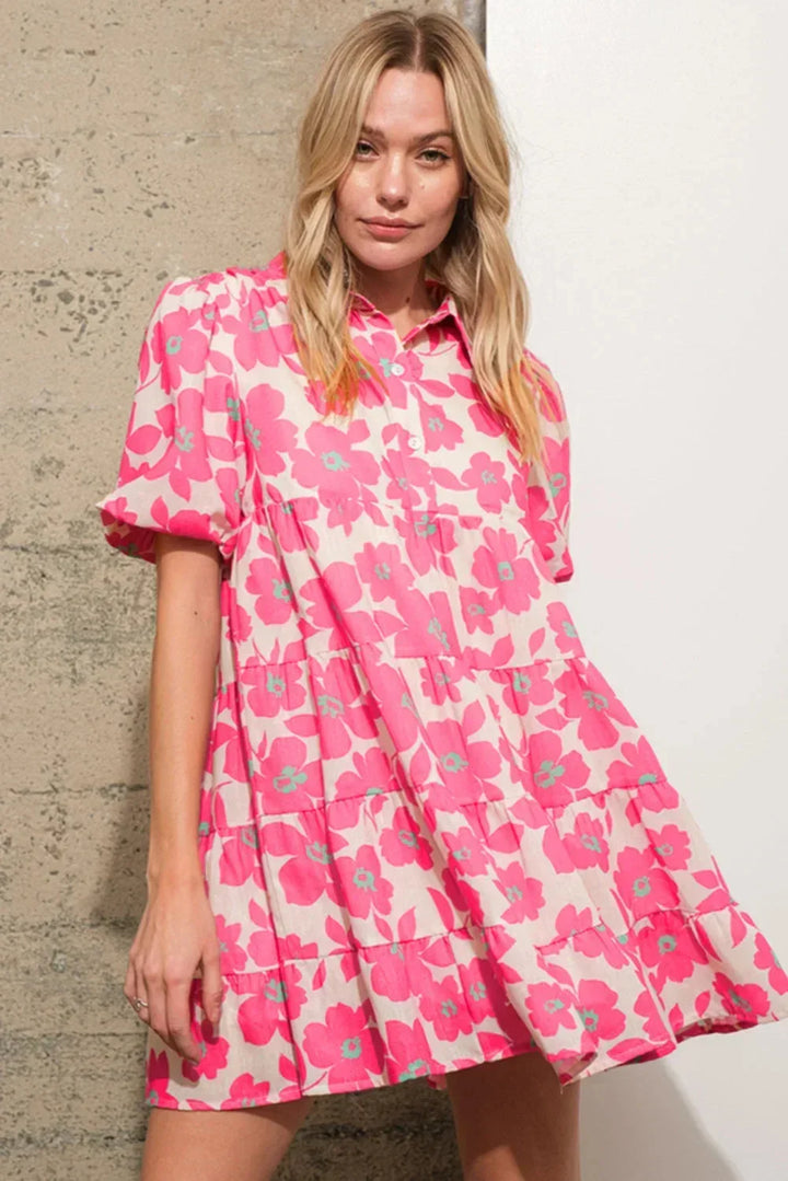 Robe courte en coton rose, motifs fleuris, volants sur le bas, manches bouffantes pour un look estival décontracté.