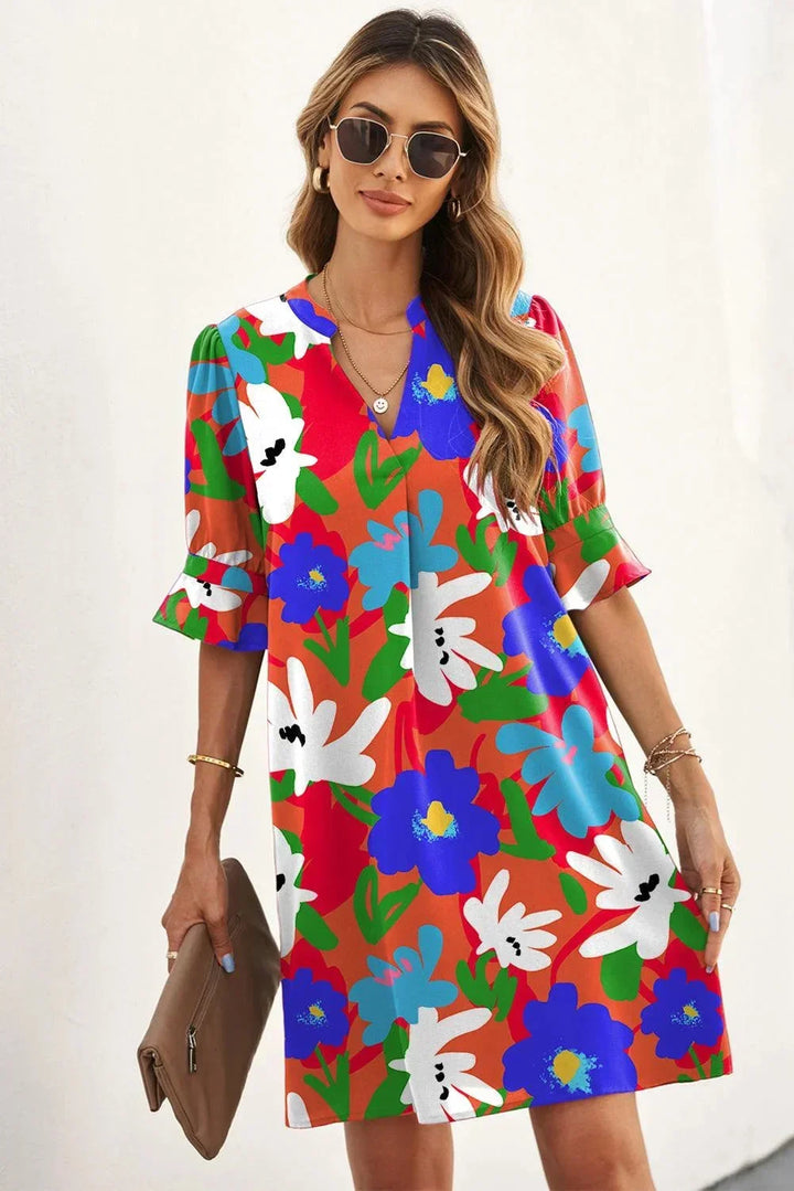 Robe courte à fleurs avec col V et manches 3/4, idéale pour l'été. Tissu léger et fluide, parfaite pour la plage.