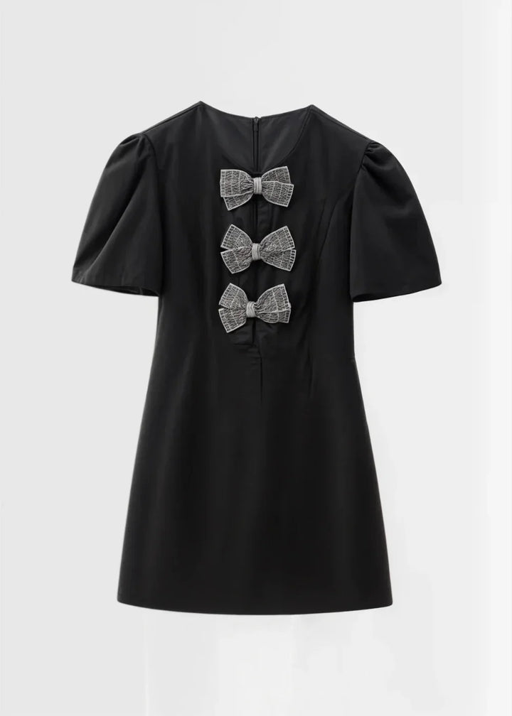 Robe courte à pois avec nœuds, manches bouffantes en tissu léger, parfaite pour une soirée estivale.