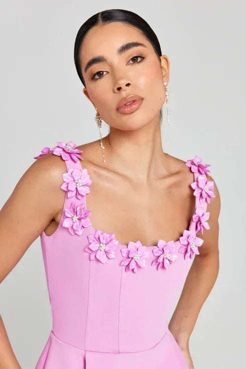 Robe courte rose sans manches avec encolure florale, détails floraux sur le tissu, idéale pour les fêtes d'été.
